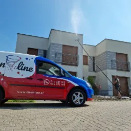 Pracownik firmy Cleanline czyści elewację nowoczesnego domu za pomocą lancy ciśnieniowej; widoczny firmowy samochód dostawczy z numerami telefonów.