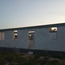 Dominatore - Surowy stan domu z betonu komórkowego w trakcie budowy, widoczne otwory okienne i drzwiowe, na tle wieczornego nieba z cienkim sierpem księżyca.
