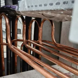 Miedziane rury klimatyzacji, widoczne narzędzie do cięcia rur. Elementy instalacji w trakcie montażu. Detal techniczny, instalacja w budynku.