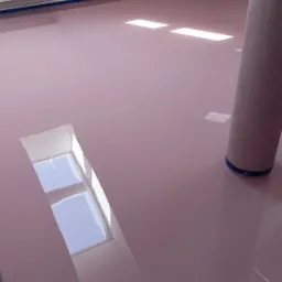 Świeżo wylana, błyszcząca, różowa powierzchnia podłogi w pokoju na poddaszu z oknem dachowym, zabezpieczona niebieską taśmą malarską przy ścianach. Na podłodze stoi rolka materiału zabezpieczającego.