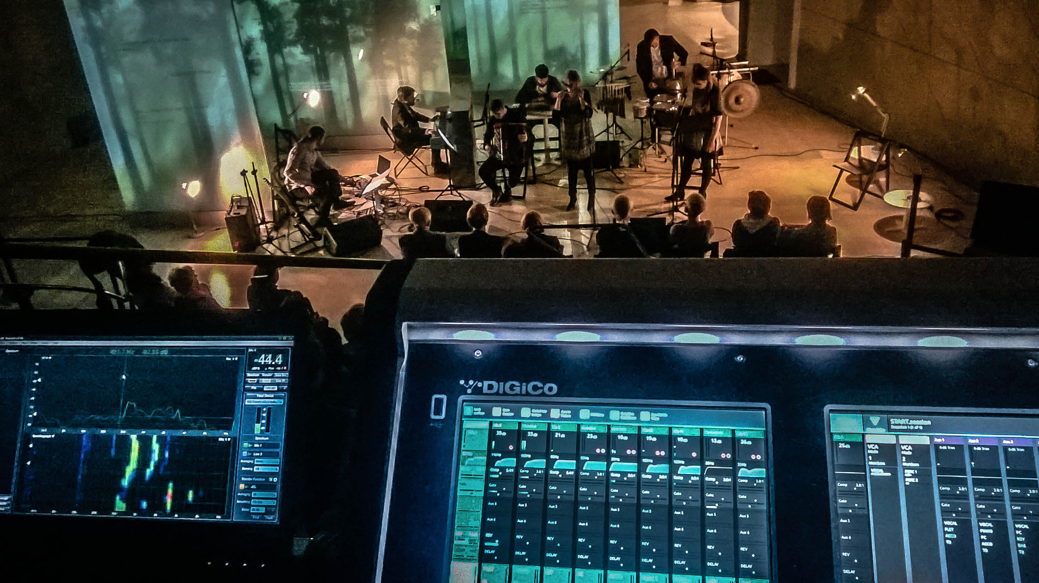 Zespół muzyczny na scenie Muzeum POLIN, widok zza konsolety oświetleniowej Digico, z widocznymi ekranami monitorów i publicznością.