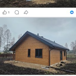 Imperial -Tim Adam Migo - Gotowy dom szkieletowy z ciemną dachówką i stolarką okienną, widoczny z dwóch perspektyw. Teren wokół domu częściowo przygotowany, w tle drzewa.