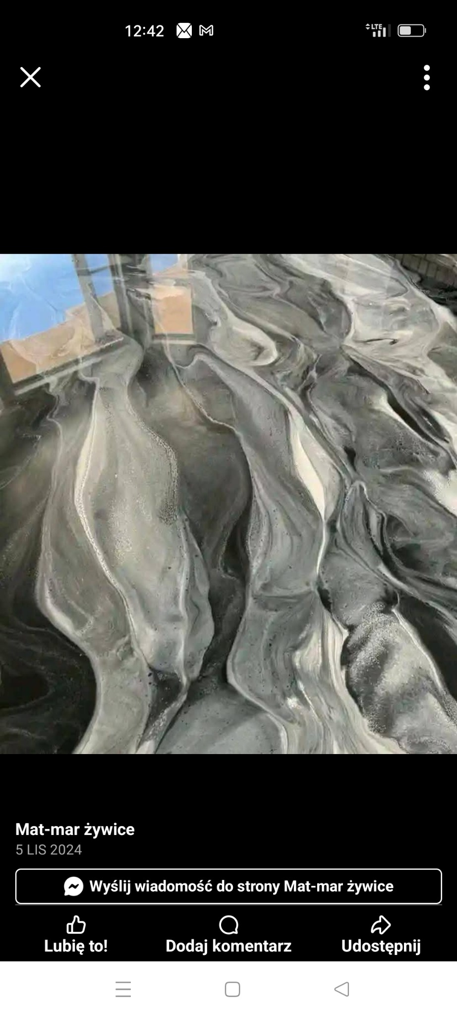 Błyszcząca posadzka żywiczna w odcieniach szarości i bieli, imitująca wzór marmuru. Widoczne refleksy światła podkreślają gładką powierzchnię.