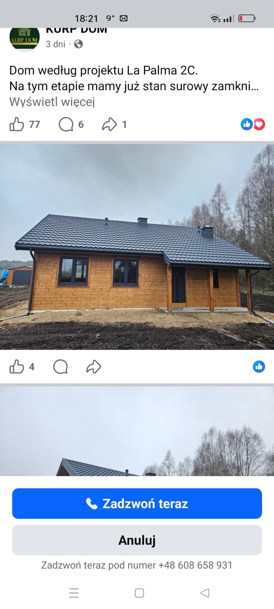 Drewniany dom szkieletowy w Woli z ciemną dachówką, w stanie surowym zamkniętym. Widoczne okna i drzwi. Tło stanowią drzewa.