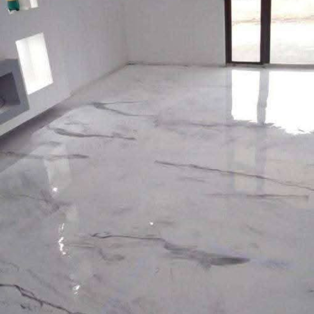 Błyszcząca, jasnoszara posadzka żywiczna z subtelnym wzorem marmurkowym w nowoczesnym wnętrzu. Widoczne odbicie światła podkreśla gładką powierzchnię.