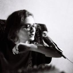 freelancer - Czarno-białe zdjęcie kobiety w okularach z nimfą na ramieniu, patrzącej w dół.