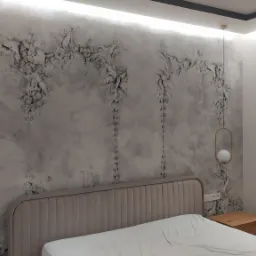 Sypialnia z dekoracyjną ścianą imitującą stiuk, oświetleniem LED podsufitowym i wiszącymi lampami kulami na złotych ramkach, nad beżowym łóżkiem z tapicerowanym zagłówkiem.