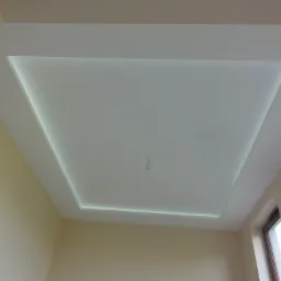 Nowoczesny sufit podwieszany z oświetleniem LED w kształcie prostokąta, widoczne niedokończone podłączenie elektryczne na środku sufitu.