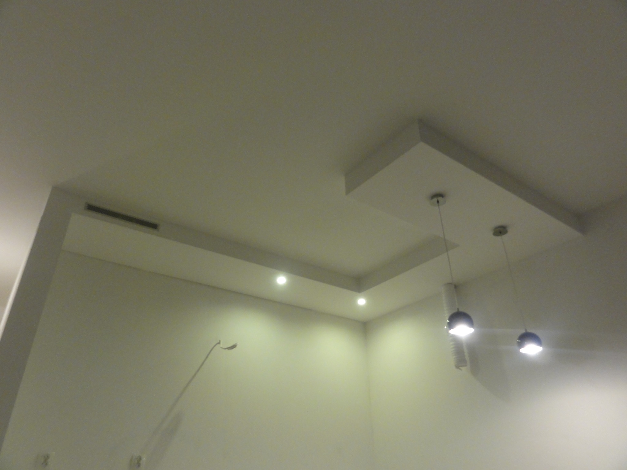 Nowoczesne oświetlenie sufitowe z dwoma wiszącymi lampami kulistymi i wbudowanymi punktami świetlnymi w Miastkowie Kościelnym, po remoncie.