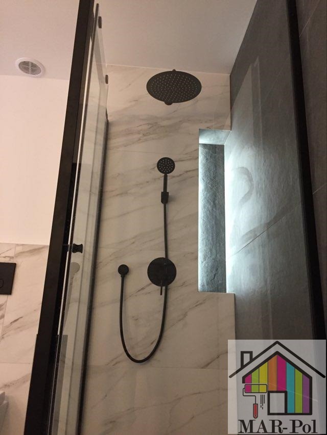 Nowoczesna kabina prysznicowa z czarną armaturą: deszczownica, słuchawka i bateria, wykończona marmurowymi płytkami z podświetlaną wnęką. W prawym dolnym rogu widoczne logo firmy MAR-Pol.