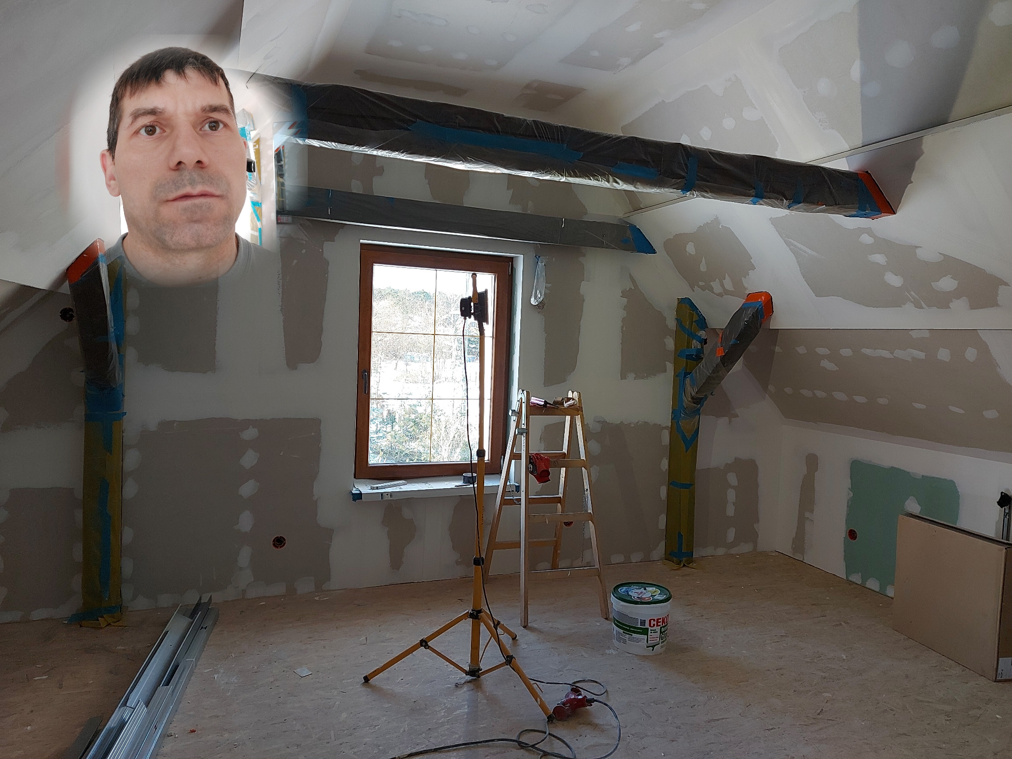 Poddasze w trakcie remontu, widoczne płyty karton gips, szpachlowane ściany, zabezpieczone rury, drabina, lampa budowlana, wiadro z masą szpachlową i profile metalowe na podłodze. Na zdjęciu...