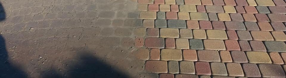 Częściowo wyczyszczona kostka brukowa, widoczna różnica w kolorze i czystości między brudną i umytą powierzchnią.