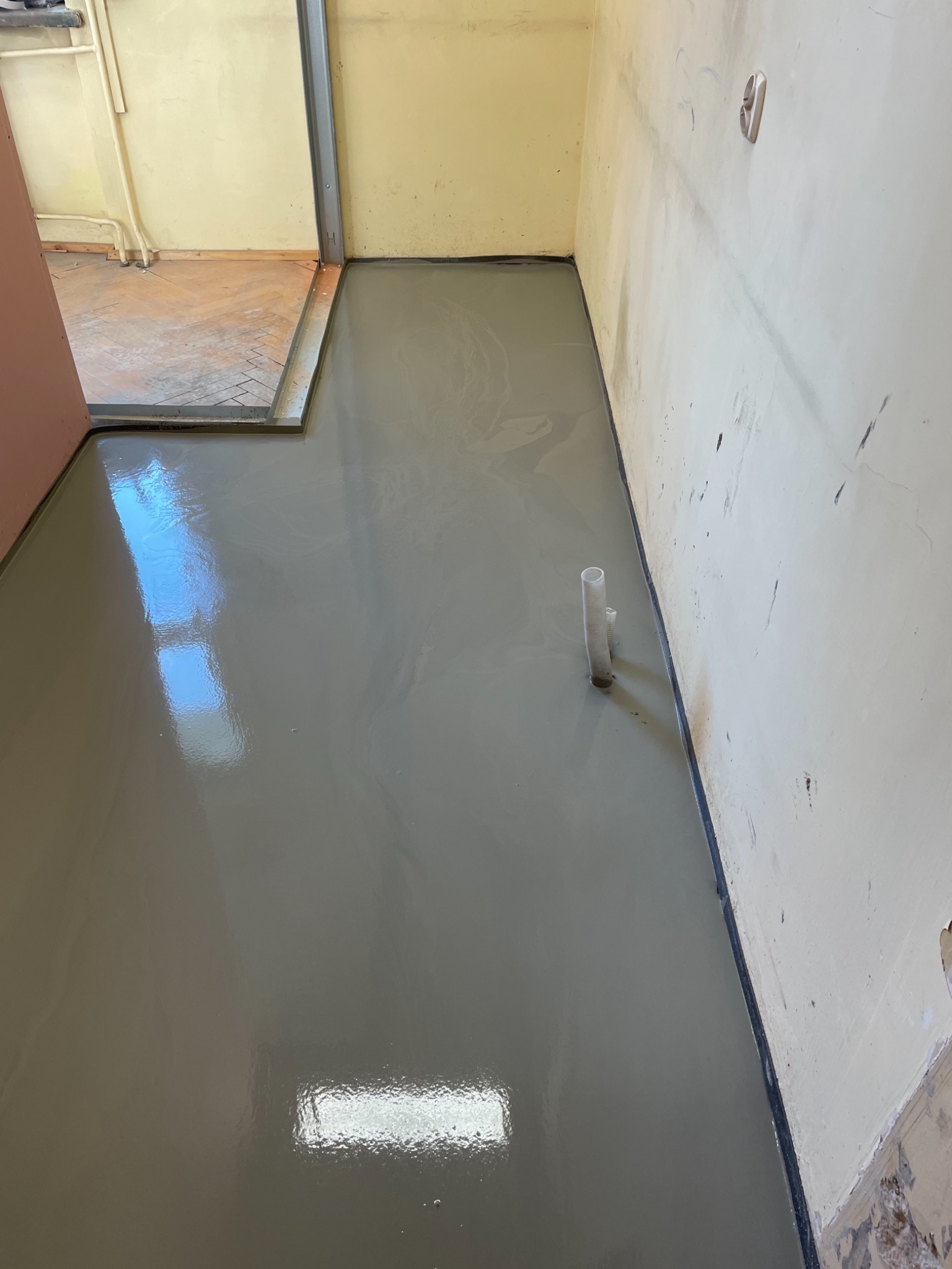 Samopoziomująca wylewka podłogowa w trakcie prac w pomieszczeniu w Zawierciu, widoczne ślady po instalacjach.
