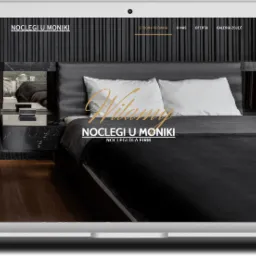 Laptop wyświetlający stronę internetową z minimalistycznym designem pokoju hotelowego, z widocznym tekstem 'Noclegi u Moniki' i menu nawigacyjnym.