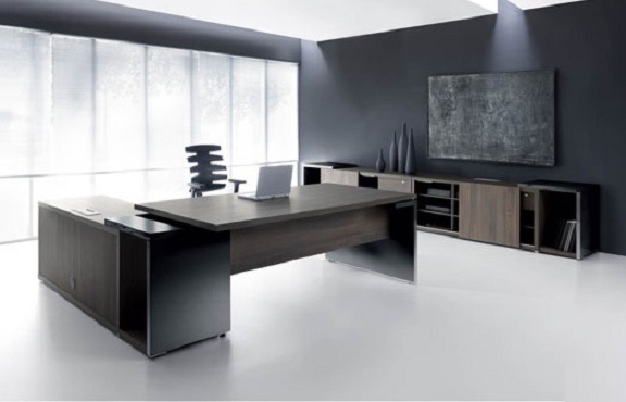 Nowoczesne biuro z ciemnobrązowym biurkiem na wymiar, ciemnoszara ściana i biała podłoga, laptop na biurku, szafka RTV w tle.