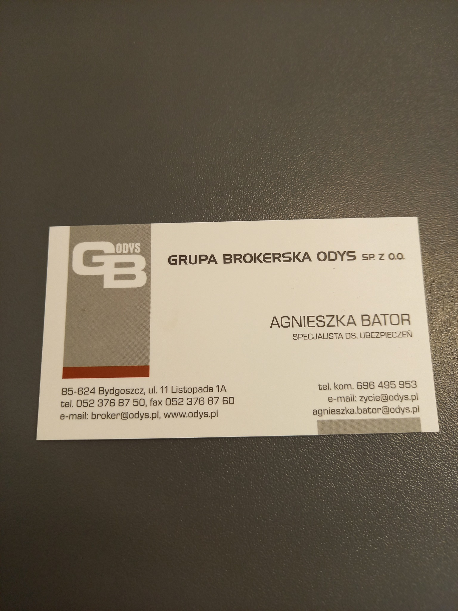 Wizytówka firmy brokerskiej Odys z Bydgoszczy, specjalisty ds. ubezpieczeń Agnieszki Bator, z logo i danymi kontaktowymi na szarym tle.
