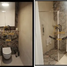 Nowoczesna łazienka z kabiną prysznicową i toaletą, wykończona płytkami w etniczne wzory. Widoczne białe meble łazienkowe i chromowane akcesoria.