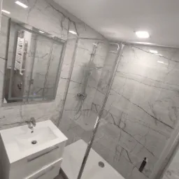 Nowoczesna łazienka z kabiną prysznicową typu walk-in, białą szafką umywalkową z dwiema szufladami i lustrem z podświetleniem LED, wykończona płytkami imitującymi marmur Carrara.