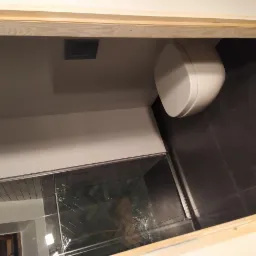 Nowoczesna łazienka z wiszącą toaletą, ciemną płytką podłogową i szklaną kabiną prysznicową z mozaiką w jodełkę, widok z góry.