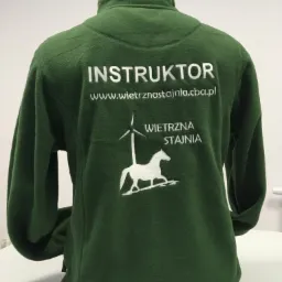 Zielona bluza polarowa z białym napisem 'INSTRUKTOR' i logo wiatraka i konia, widok z tyłu.