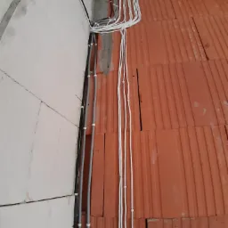 Instalacja elektryczna w trakcie budowy, widoczne kable prowadzone po ścianie z betonu komórkowego i stropie z pustaków ceramicznych.