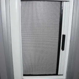 Zamknięta moskitiera rolowana w oknie, biała rama, widok z wnętrza w Lusówku.