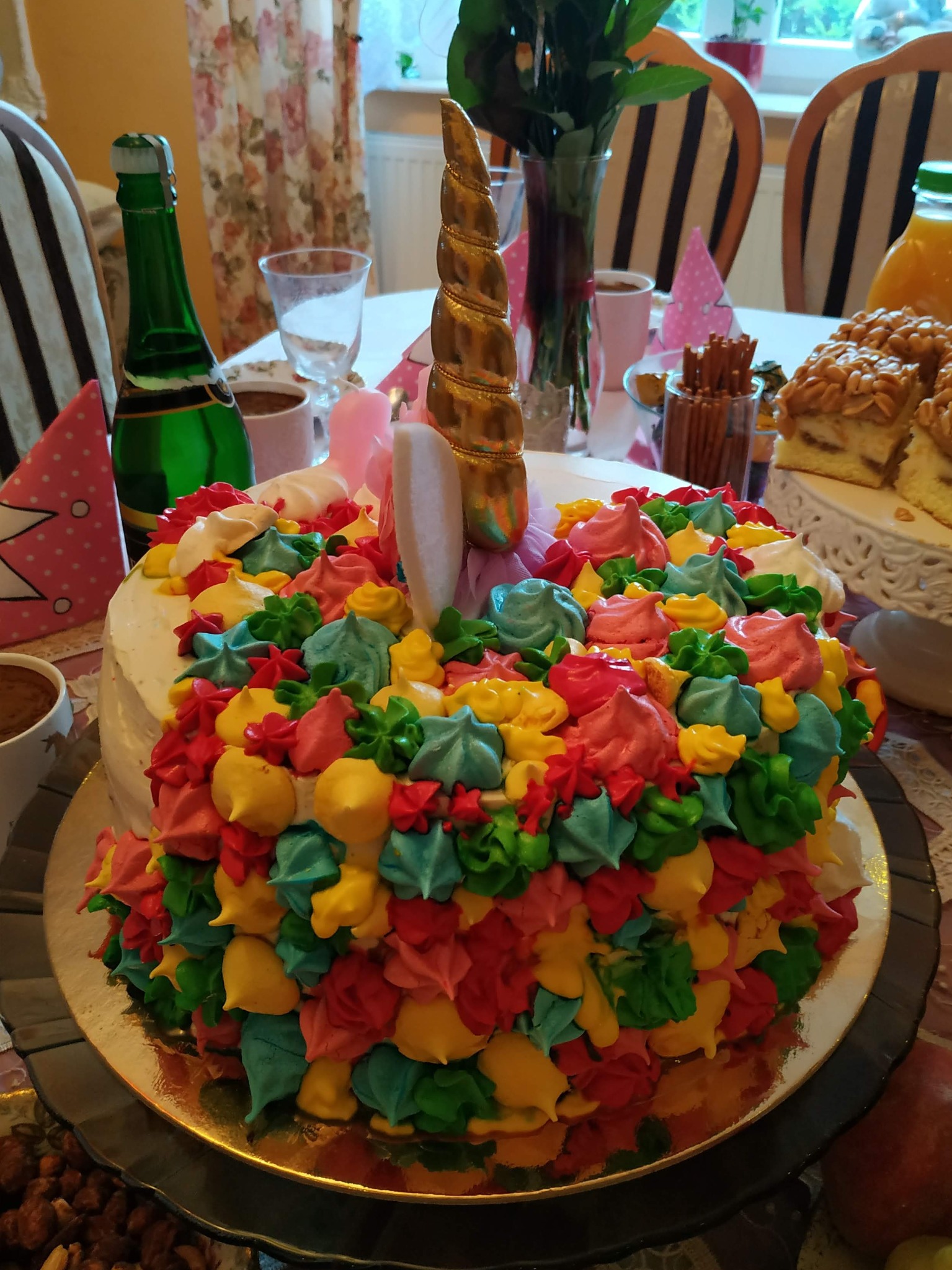 Tort jednorożec z kolorową dekoracją z kremu na stole w Czechowicach-Dziedzicach, otoczony dekoracjami urodzinowymi i napojami.