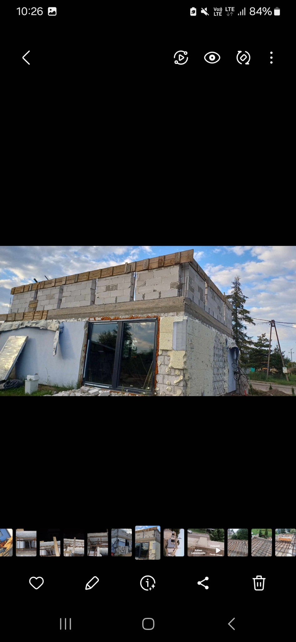 Budynek w trakcie ocieplania, widoczna warstwa styropianu, bloczki betonowe na górze i zamontowane okno z ciemną ramą.