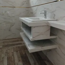 Umywalka z szafką i półkami wykończona marmurowym wzorem w łazience w Padwi Narodowej, widoczne płytki na ścianach i podłodze.