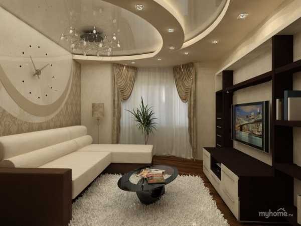 Elegancki salon z narożną sofą w odcieniach bieli i brązu, dekoracyjnym zegarem ściennym, podwieszanym sufitem z oświetleniem punktowym i kryształowym żyrandolem, oraz ścianką telewizyjną z półkami.