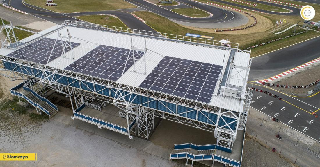 Widok z góry na konstrukcję z panelami słonecznymi na dachu, umieszczoną obok toru kartingowego w Słomczynie, z widocznymi schodami i elementami konstrukcyjnymi.