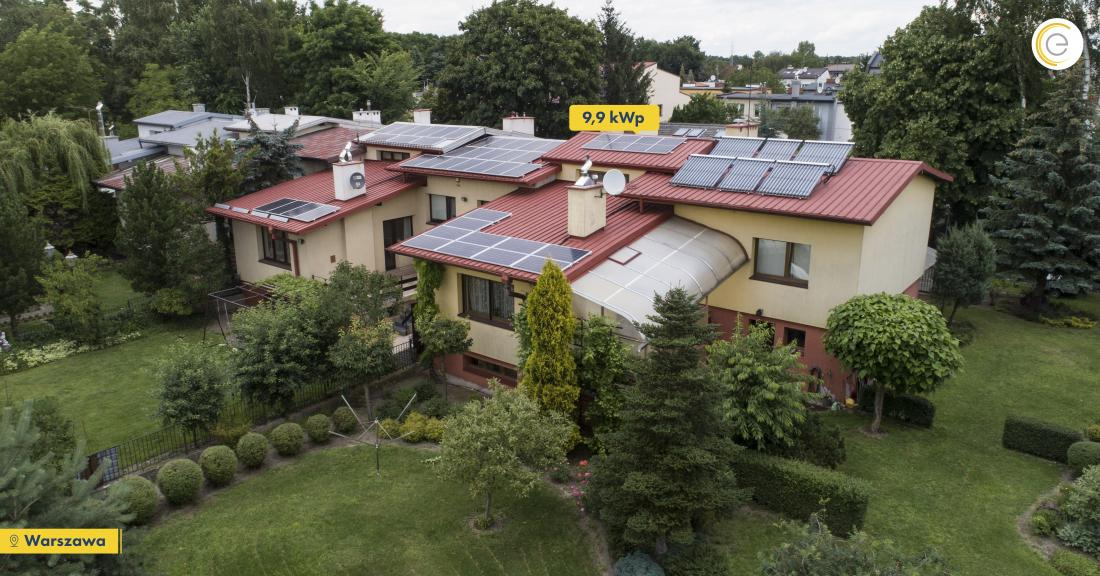 Dom jednorodzinny z panelami słonecznymi i kolektorami słonecznymi na czerwonym dachu, widok z góry, zielony ogród, Warszawa.