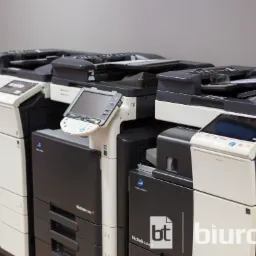 Rząd nowych, wielofunkcyjnych kserokopiarek Konica Minolta Bizhub C286 i C364, ustawionych w magazynie, z widocznym logo firmy Biurotech na jednej z nich.