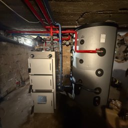 Lubas Serwis - Nowoczesny piec CO z zasobnikiem w piwnicy, instalacja z rur miedzianych i plastikowych, widok na ceglany mur i betonowy sufit. CEFF, Galmet.