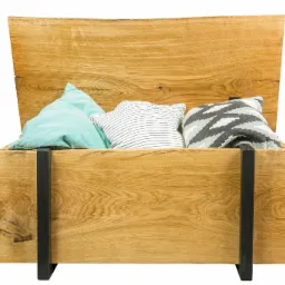 Otwarta skrzynia z jasnego drewna z trzema poduszkami w środku: turkusową, w biało-szare paski i szarą w geometryczny wzór, wsparta na czarnych metalowych nogach.