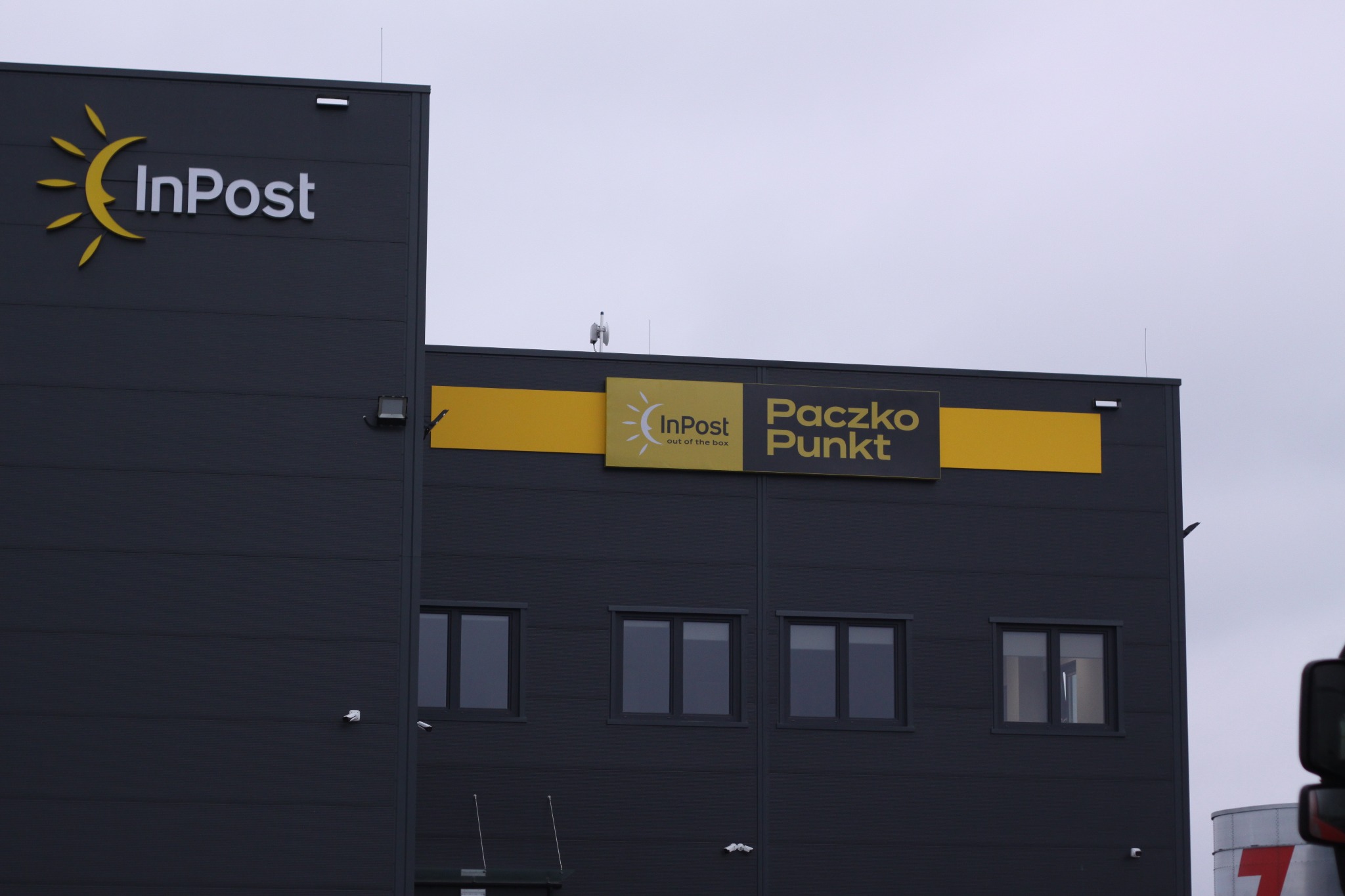 Budynek InPost Paczko Punkt z widocznymi oknami i logotypami, na zewnątrz szara, pochmurna pogoda.