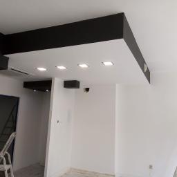 WZ. Wykończenia wnętrZ - Nowoczesny sufit podwieszany z czarnymi elementami i wpuszczonym oświetleniem w trakcie montażu w Rybniku, widoczne drabiny malarskie.