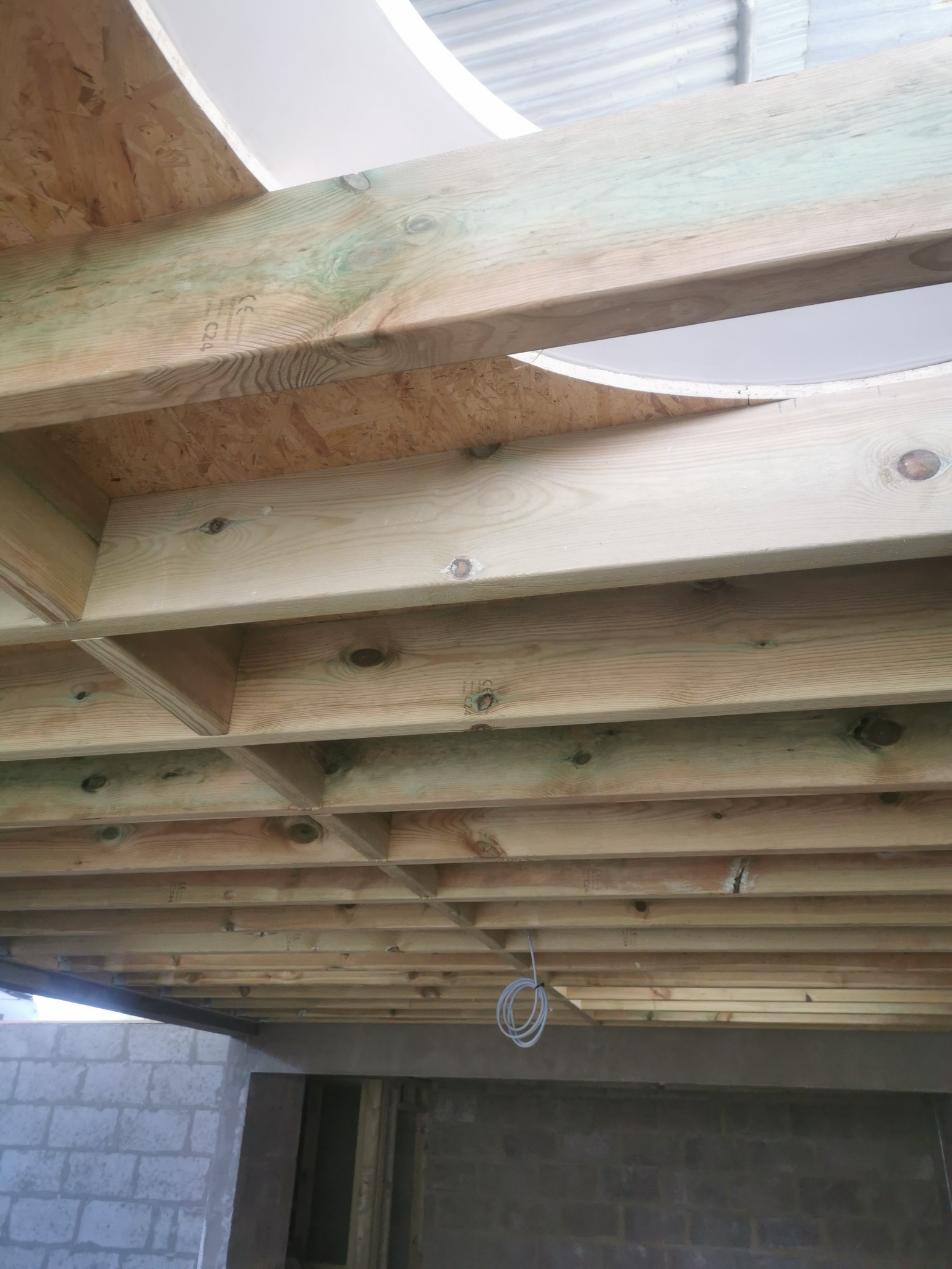 Drewniana konstrukcja stropu z okrągłym otworem na oświetlenie, widok z dołu, w surowym stanie w Londynie.