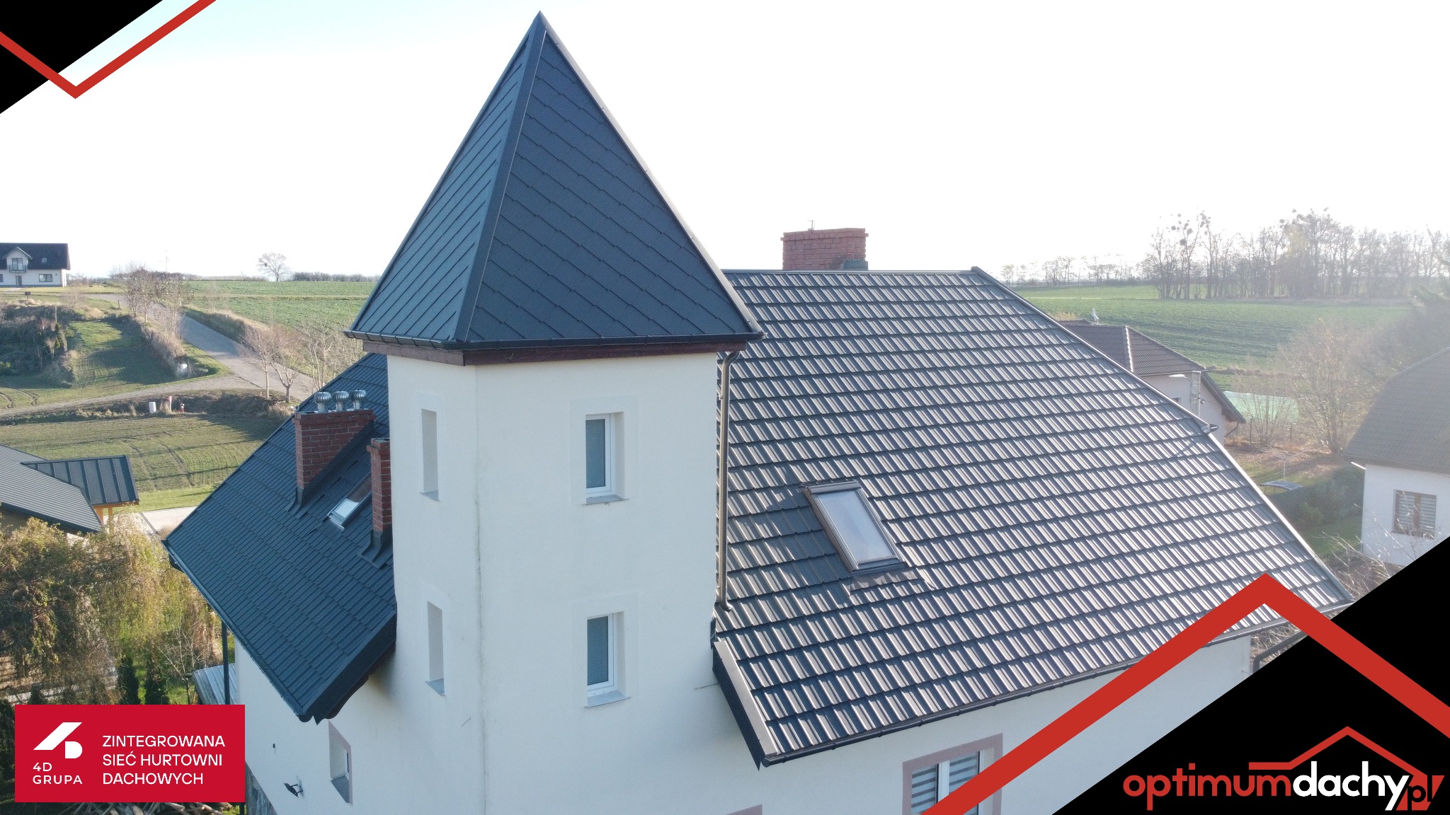 Elewacja domu z wieżyczką i dachem pokrytym ciemną dachówką, widok z góry. Na dachu okno połaciowe. W tle krajobraz wiejski i inne budynki.