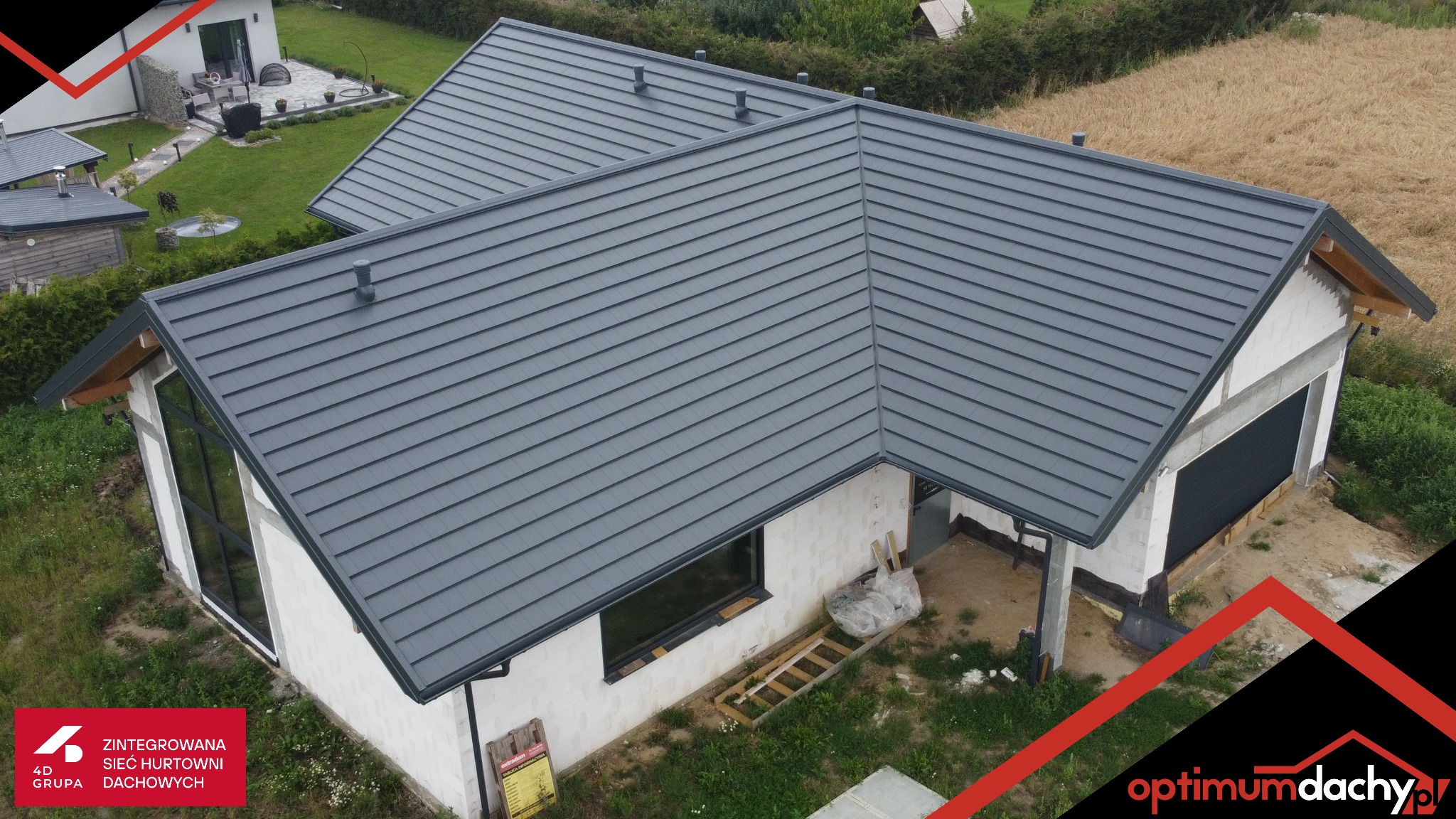 Nowoczesny dom w trakcie budowy z szarym dachem z blachy na gotowej konstrukcji. Widok z góry ukazuje detale pokrycia i otoczenie budynku.