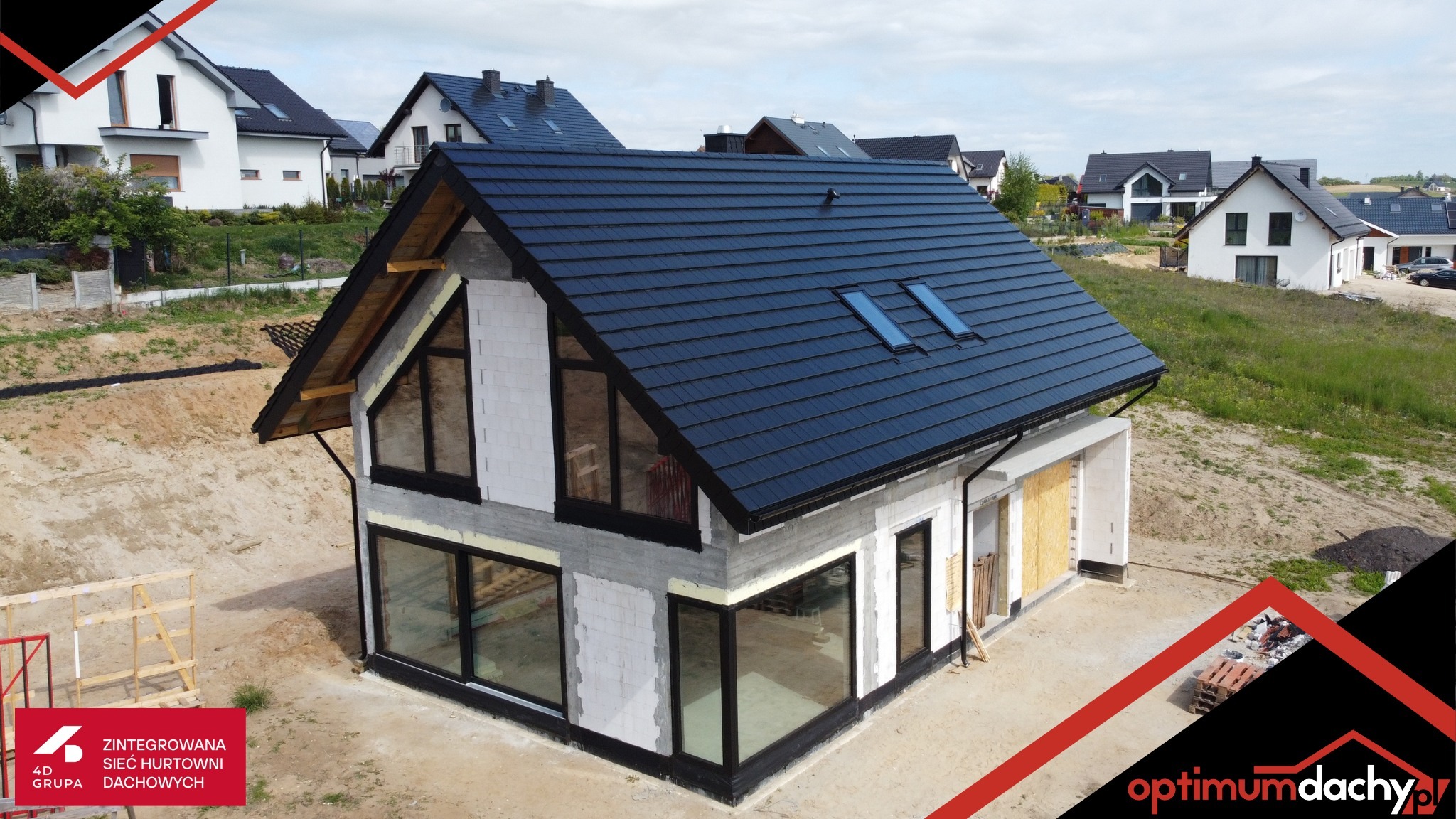 Dom w budowie z czarnym dachem z dachówką i oknami dachowymi w Tczewie. Widok z góry ukazuje konstrukcję i otoczenie.