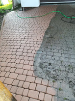 Częściowo umyta kostka brukowa w odcieniach brązu, widoczna różnica w kolorze i czystości między umytą a brudną powierzchnią, w tle zwinięty wąż ogrodowy.