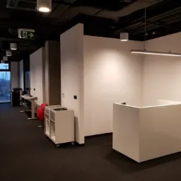 Nowoczesne biuro z recepcją, oświetleniem LED i znakiem ewakuacyjnym, widok na zewnątrz przez okno.