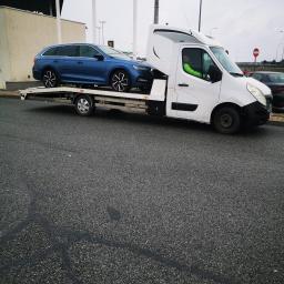 G. S. M. Transport - Niebieska Skoda Octavia kombi przewożona na białej lawecie na parkingu stacji benzynowej BP, widoczny kierowca w zielonej kamizelce.