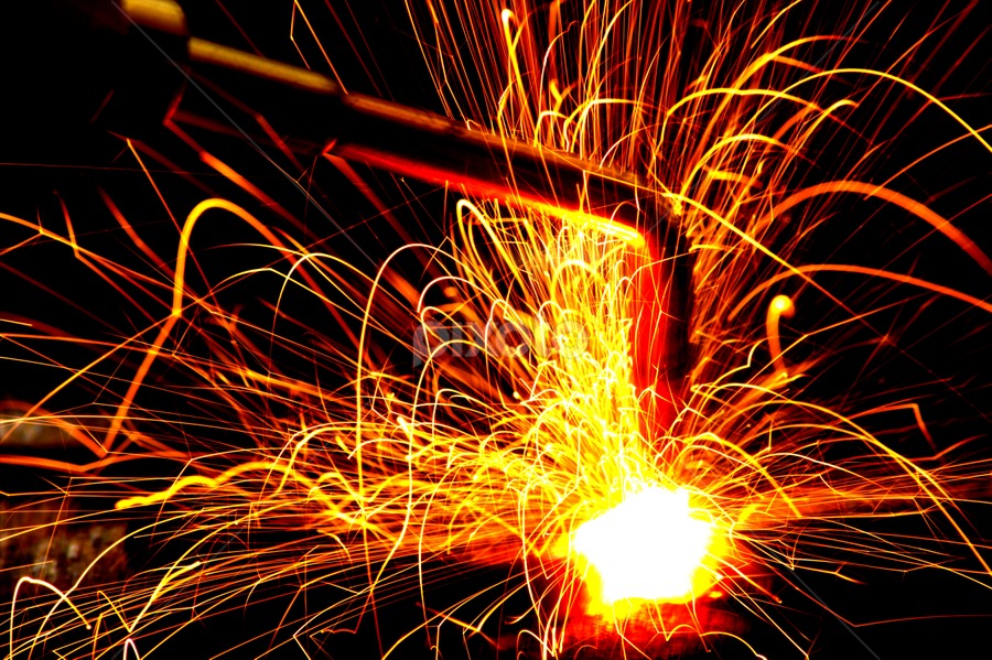 Intensywne iskry podczas spawania metalu, widoczne w ciemności, z bliska uchwycony moment obróbki.