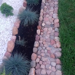 WIOLETTA Wojciechowska - Ogród z dekoracyjnym korytem z kamieni, ozdobnymi trawami i białym żwirem, widok z góry.