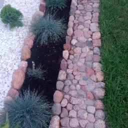 Ogród z dekoracyjnym korytem z kamieni, ozdobnymi trawami i białym żwirem, widok z góry.