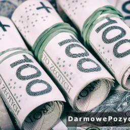 Trzy zrolowane pliki banknotów 100-złotowych, spięte gumkami, leżące na tle rozrzuconych banknotów. Widoczny napis 'STO ZŁOTYCH' na każdym rulonie.