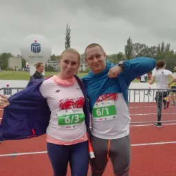 Dwoje biegaczy pozuje na bieżni po biegu, z numerami startowymi 6/1 i 6/3, w tle balon reklamowy Banku Polski.