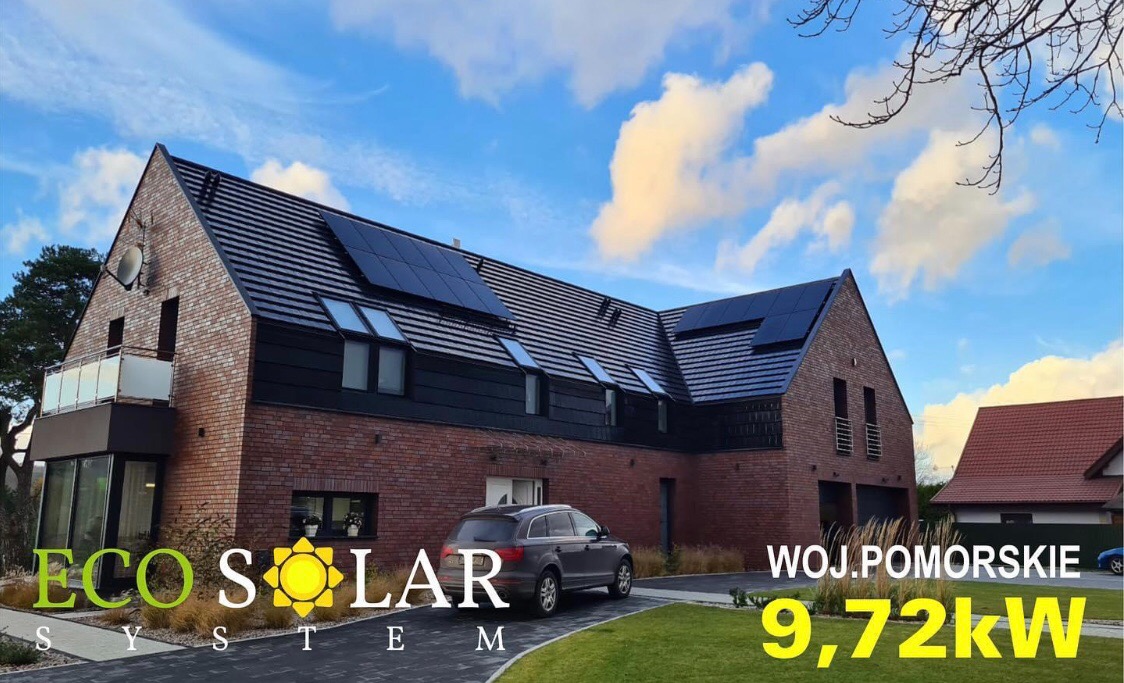 Dom z cegły z zainstalowanymi panelami słonecznymi na dachu, szare auto na podjeździe, logo firmy w lewym dolnym rogu, informacja o mocy instalacji w prawym dolnym rogu.